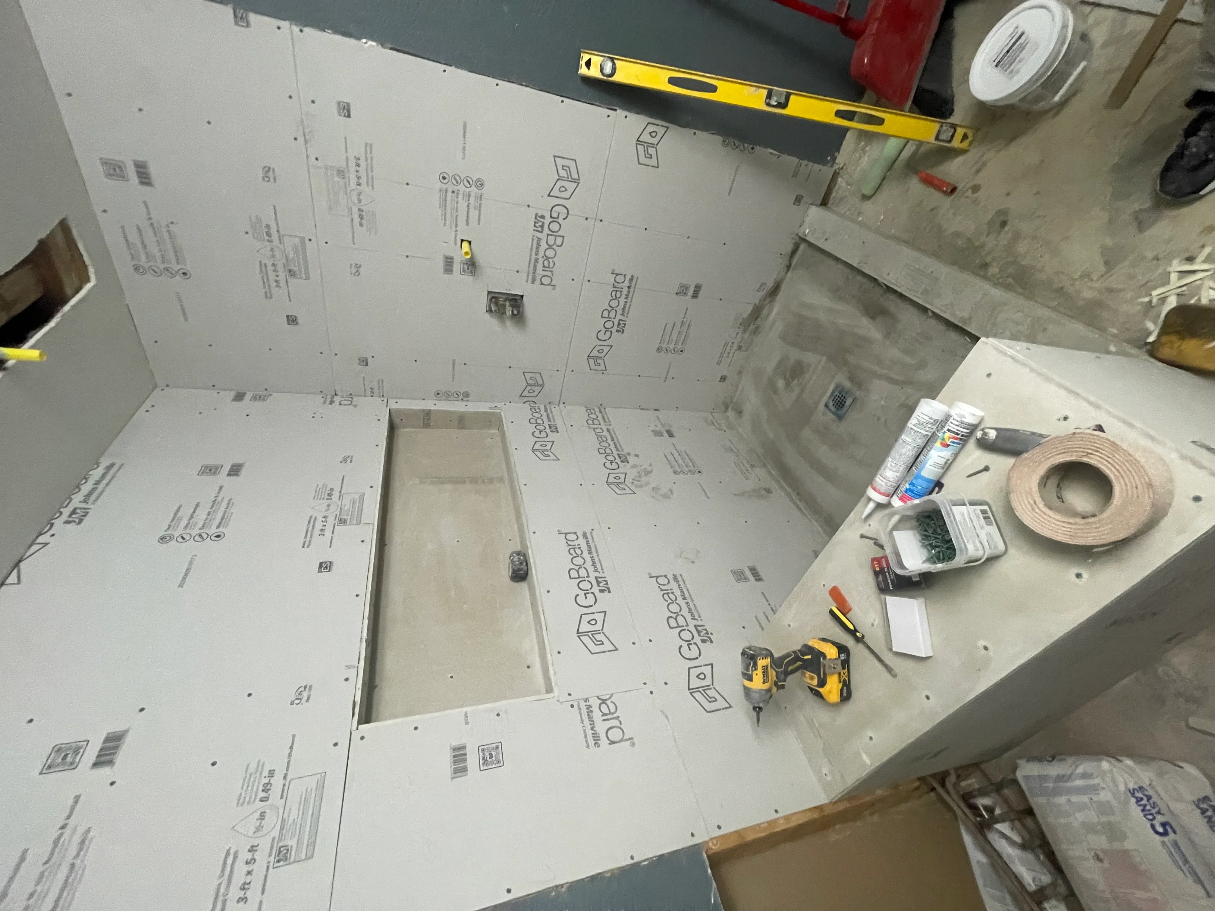 Drywall sheets installed on ceiling with cutouts for fixtures, joint tape and sealant materials visible