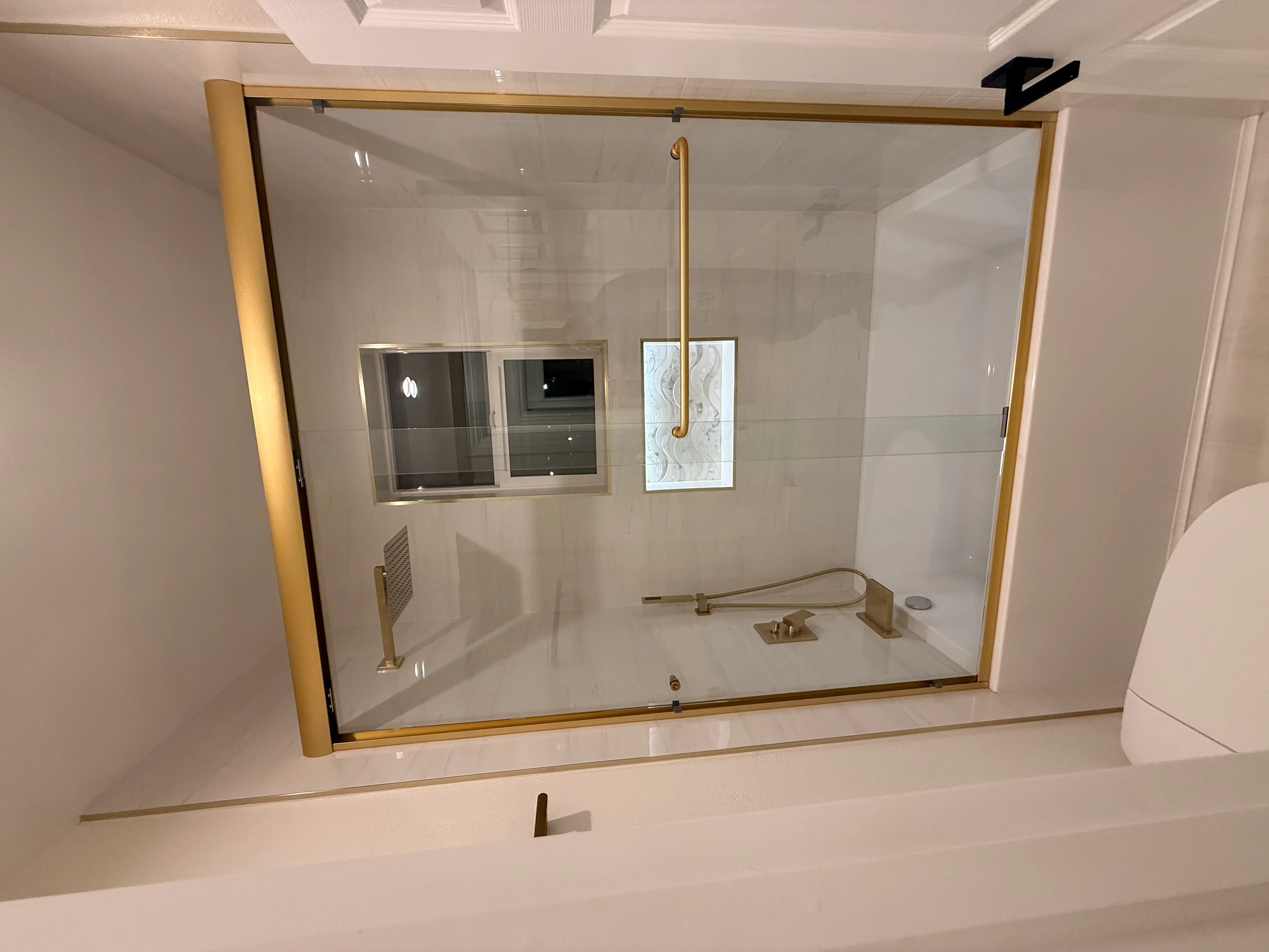 Frameless glass shower enclosure with brushed gold frame and integrated niche shelving