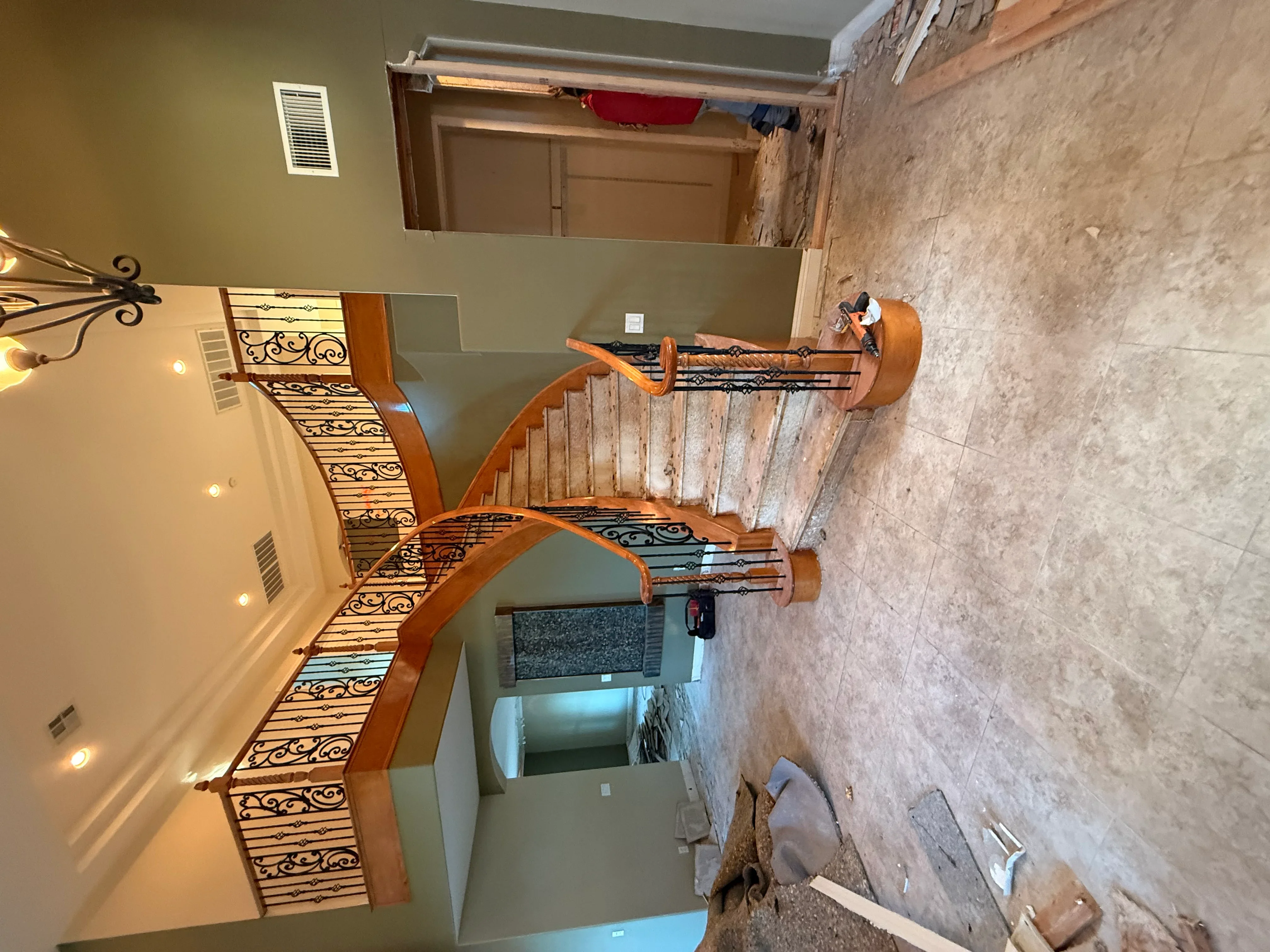 Renovated staircase with hardwood steps, wrought iron railings, sage green drywall, and recessed lighting