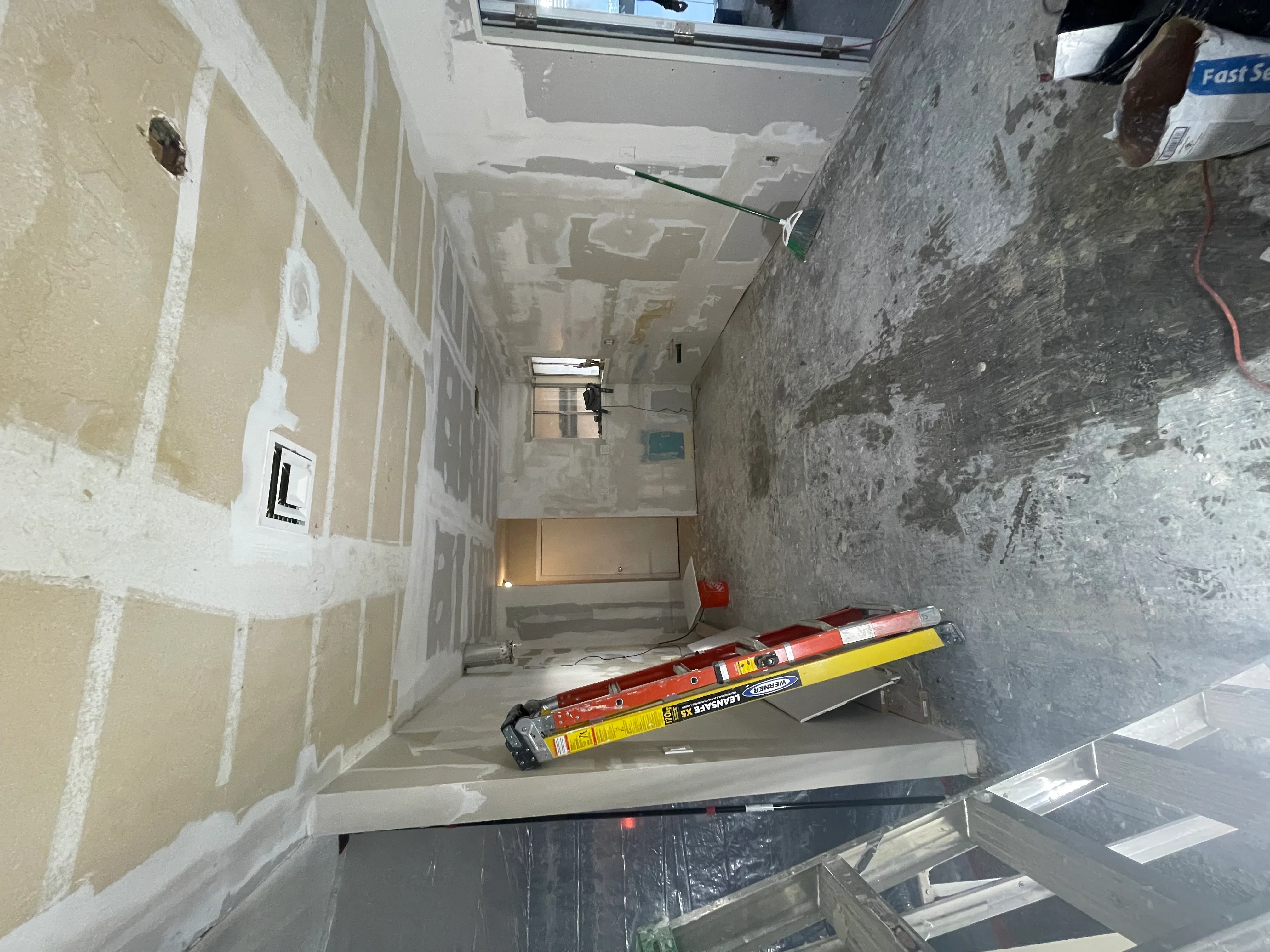 Bathroom under renovation with drywall mudding, electrical outlets, and concrete subfloor